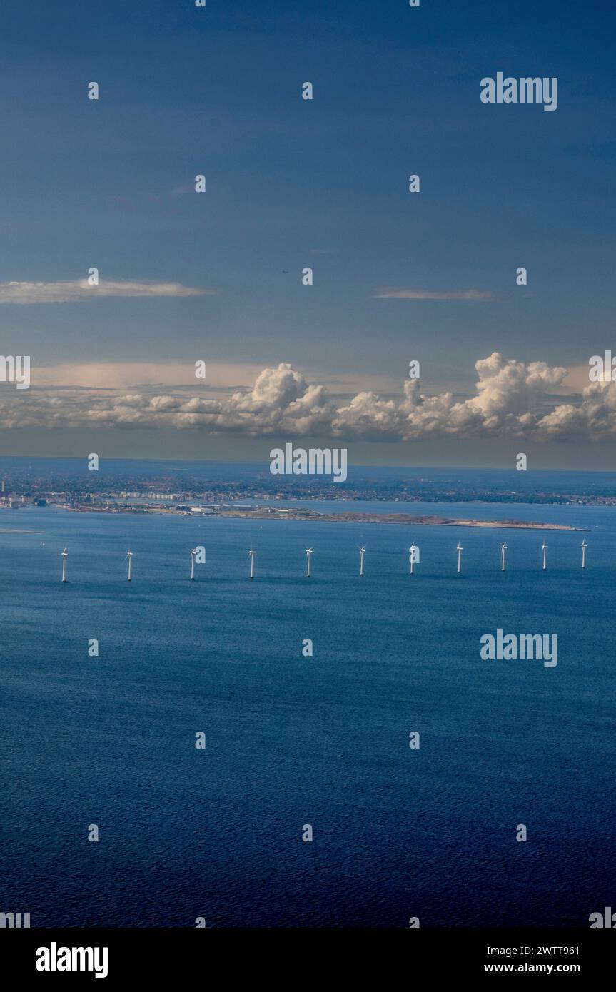Un tranquillo paesaggio marino con turbine eoliche all'orizzonte sotto un cielo nuvoloso. Foto Stock