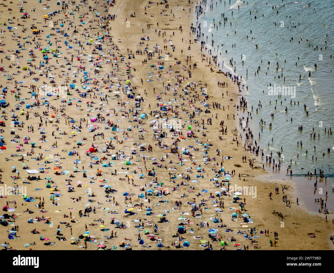 Un'intensa giornata in spiaggia con folle che si godono il sole e il mare Foto Stock