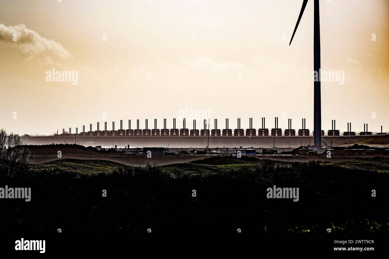 Turbine eoliche ed edifici industriali al tramonto Foto Stock