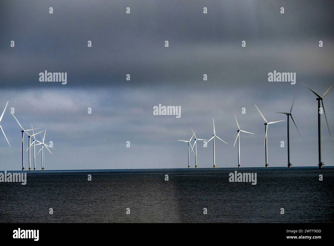 Turbine eoliche alte contro un cielo lunare sull'oceano Foto Stock