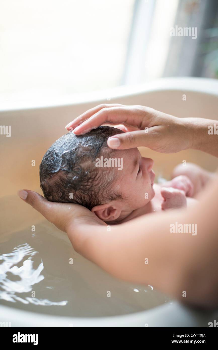 Un momento tenero come un neonato viene bagnato dolcemente Foto Stock