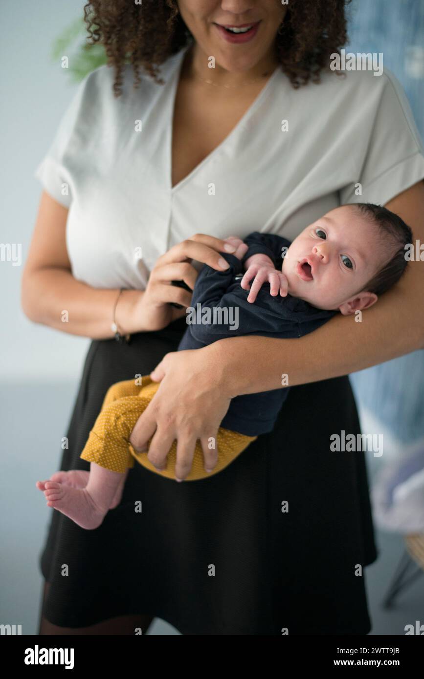 Una madre che tiene in braccio il neonato con un sorriso tenero. Foto Stock