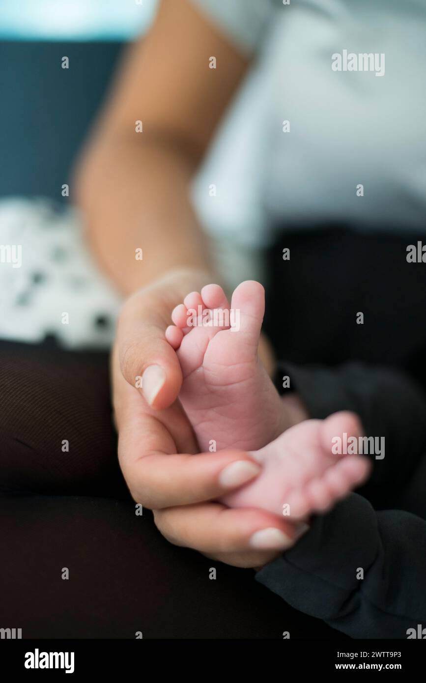 Un momento tenero con un genitore che tiene i piccoli piedi del bambino. Foto Stock