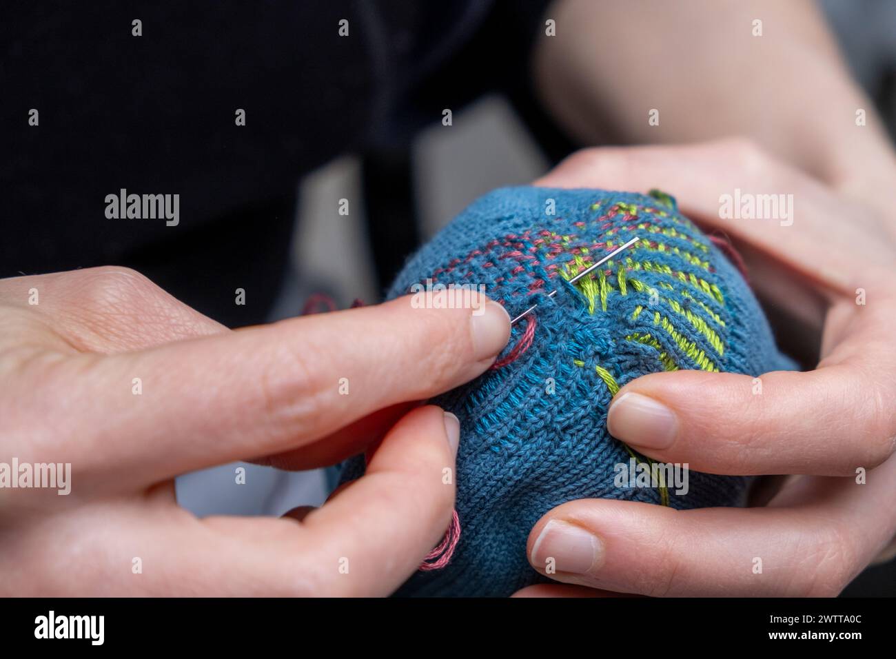 Curare i vestiti. Calza per riparazione e rimontaggio visibile. Cavolo vecchi calzini, riduzione degli sprechi, moda lenta. Concetto di riparazione, attenzione selettiva. Foto Stock