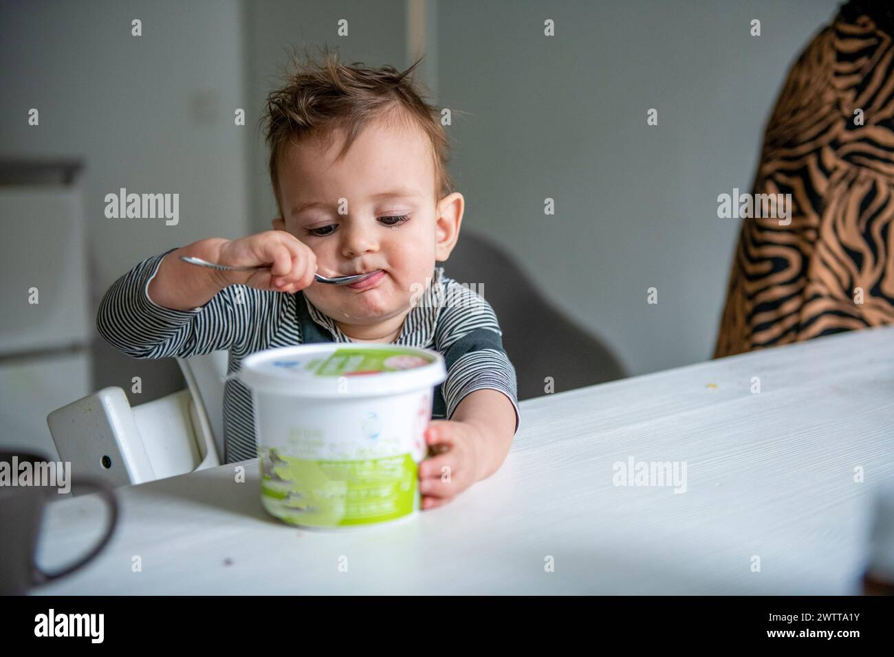 Il bambino si gusta un pasto con un cucchiaio grande Foto Stock