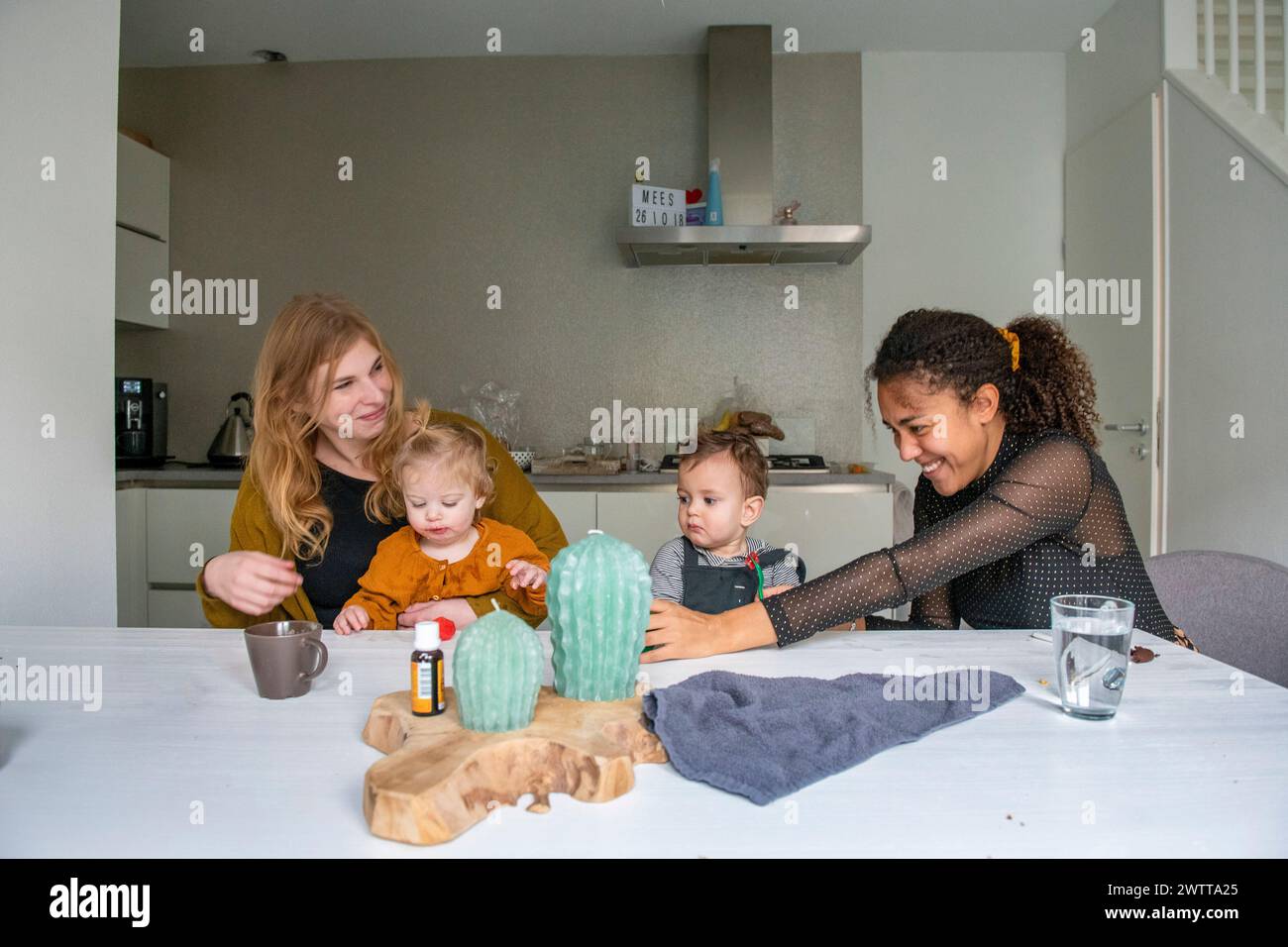 Divertimento per tutta la famiglia: Due adulti giocano con i bambini in un accogliente tavolo da cucina. Foto Stock