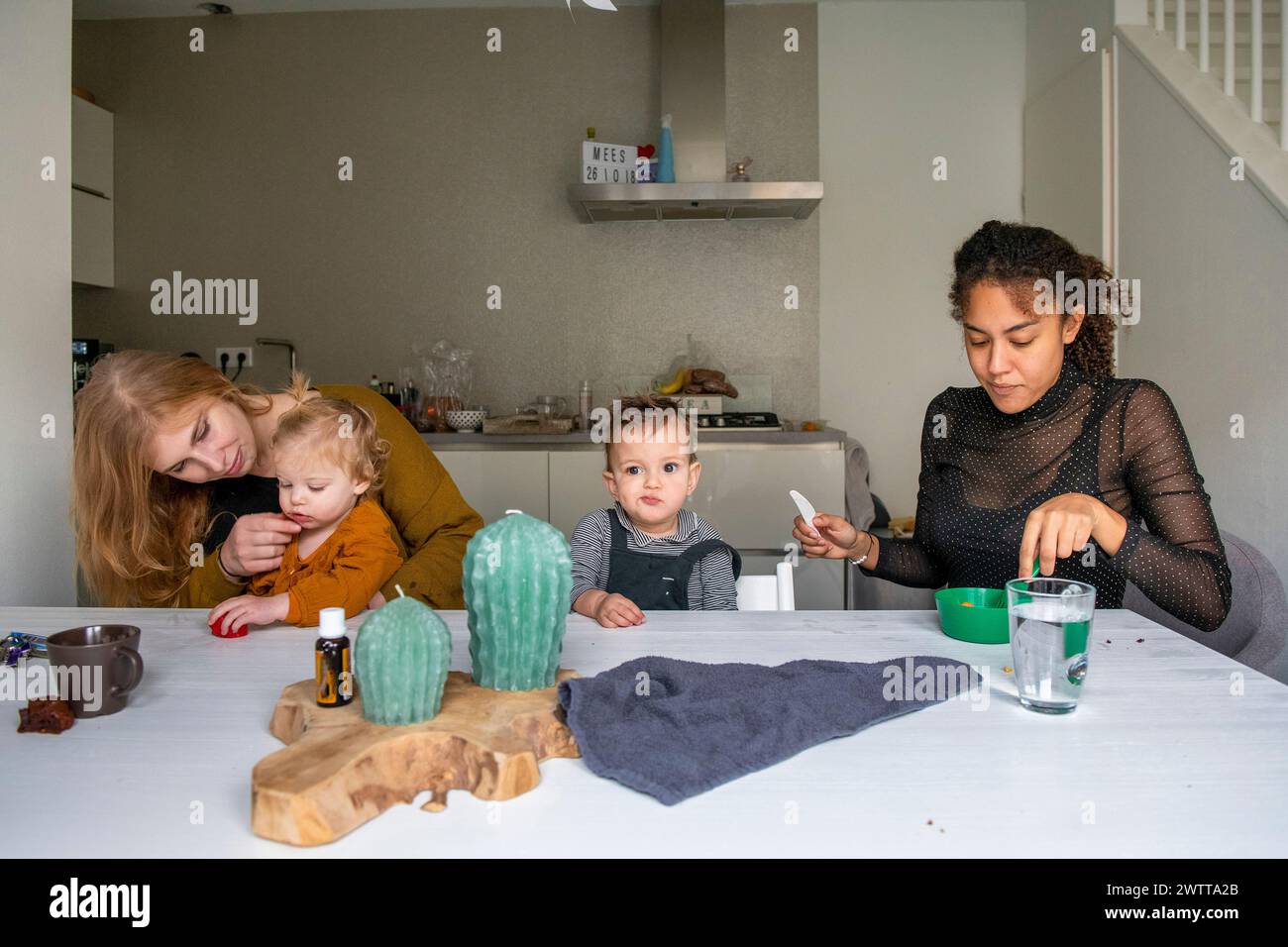 Tempo in famiglia al tavolo della cucina con spuntini e attività. Foto Stock