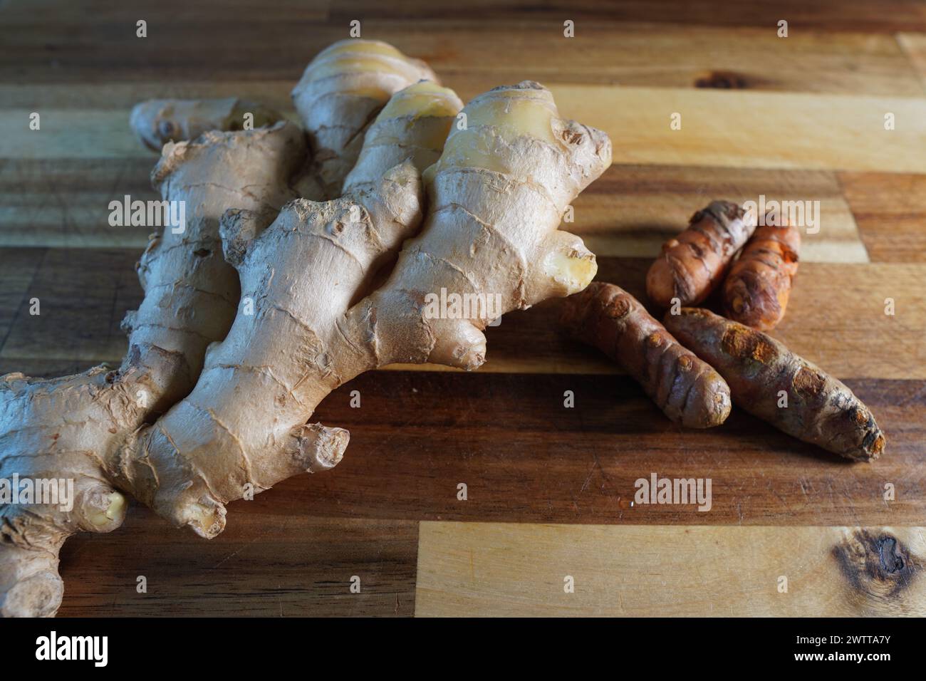 Zenzero e curcuma sul tagliere, luce diretta da destra Foto Stock
