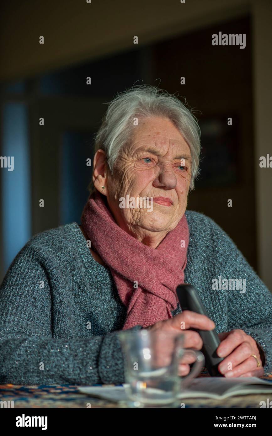 Una donna anziana ha perso il pensiero tenendo in mano un telecomando Foto Stock