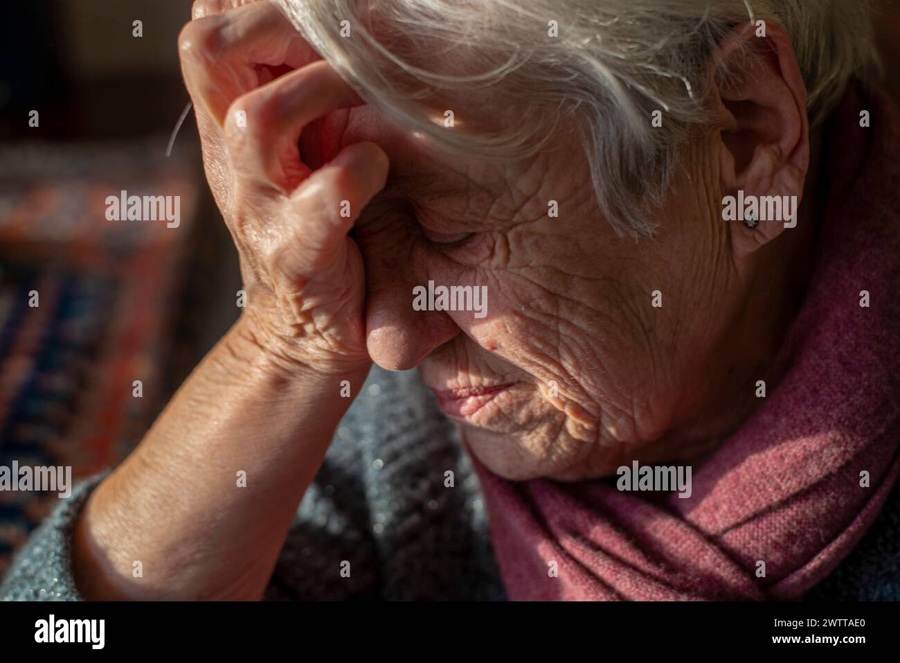 Una donna anziana, molto attenta al pensiero, o forse con mal di testa. Foto Stock
