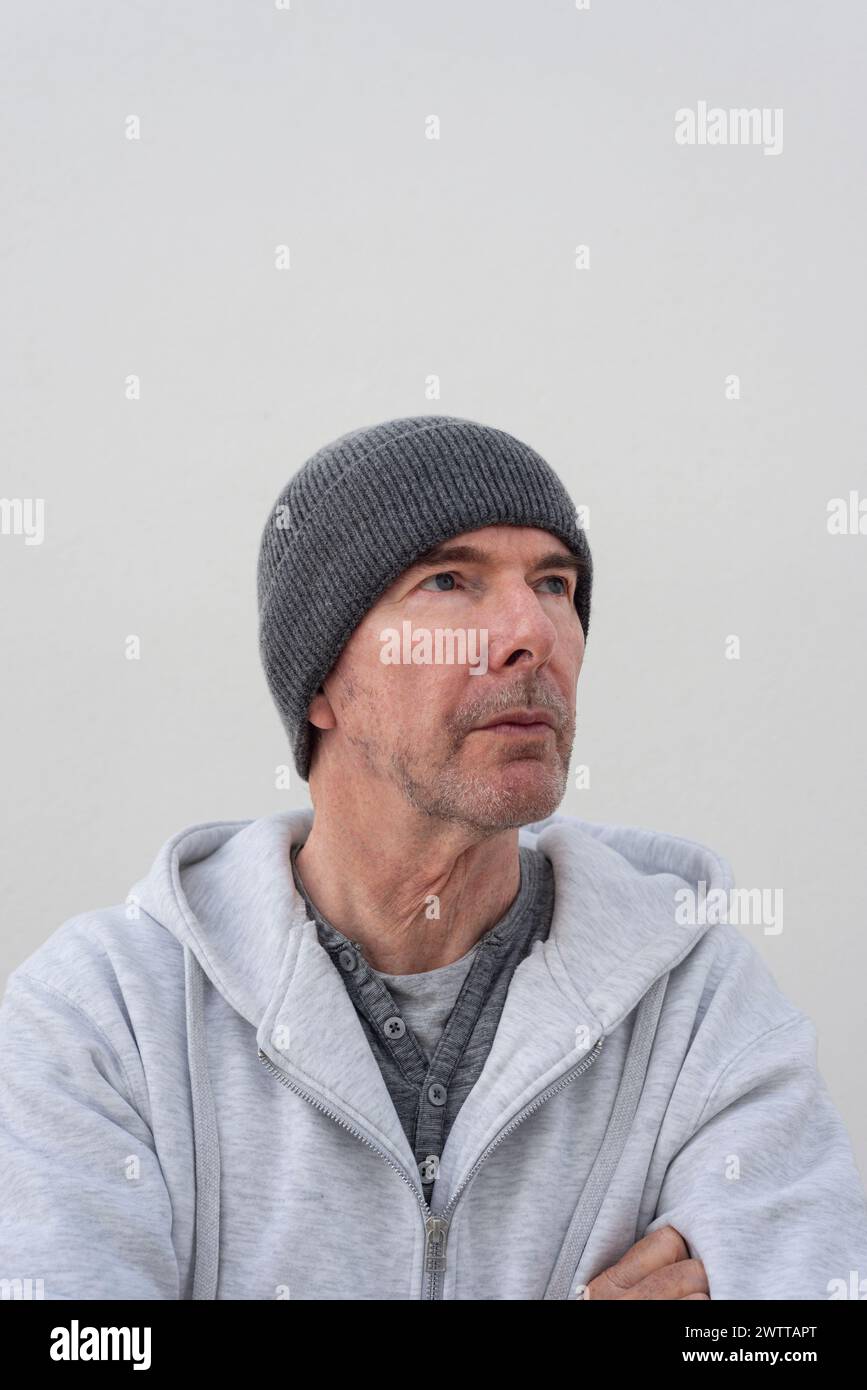 Ritratto di un bell'uomo maturo che indossa un cappello a maglia, che guarda lontano Foto Stock