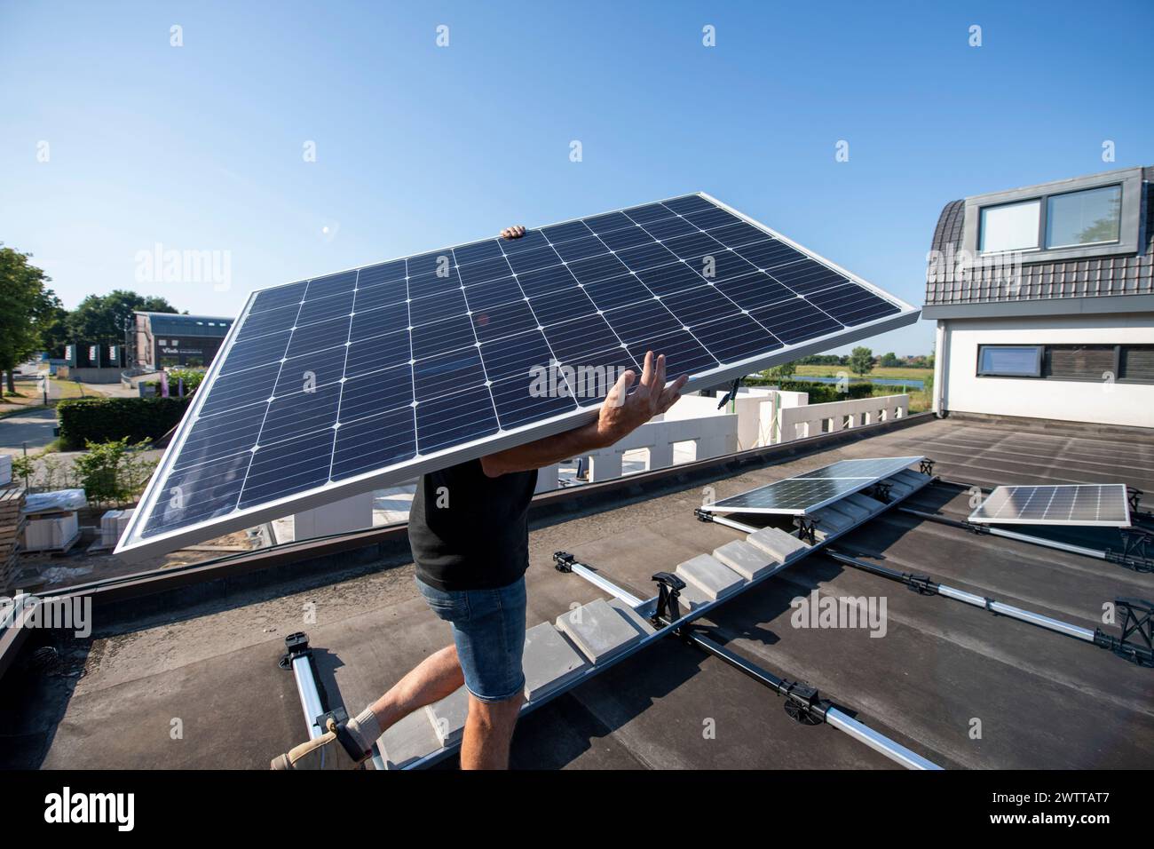 Uomo che installa un pannello solare su un tetto in una giornata di sole Foto Stock