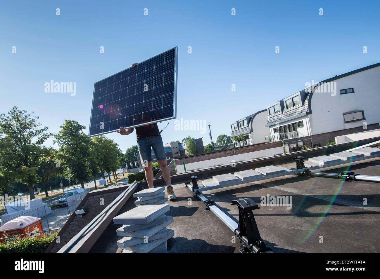 Lavoratore che installa un pannello solare su un tetto in una giornata di sole. Foto Stock