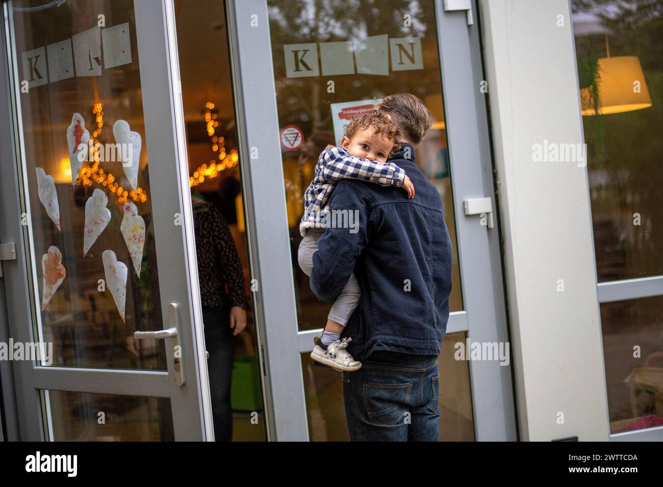 Un momento tenero come un genitore abbraccia un bambino fuori da una casa accogliente. Foto Stock