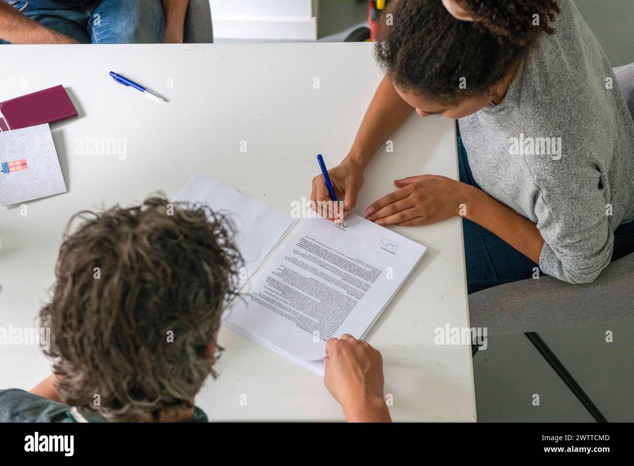 Due persone che collaborano a un documento a un tavolo bianco. Foto Stock