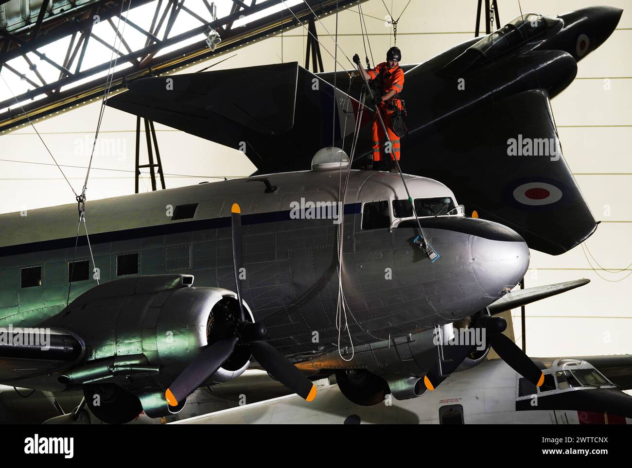 Gli specialisti dell'accesso alla fune industriale si lanciano al Royal Air Force Museum Midlands, a Cosford, vicino a Telford, nello Shropshire, per accedere a una mostra di aerei sospesi esposta nella National Cold War Exhibition, durante la pulizia e la manutenzione annuale di alto livello degli aeromobili. Data foto: Martedì 19 marzo 2024. Foto Stock