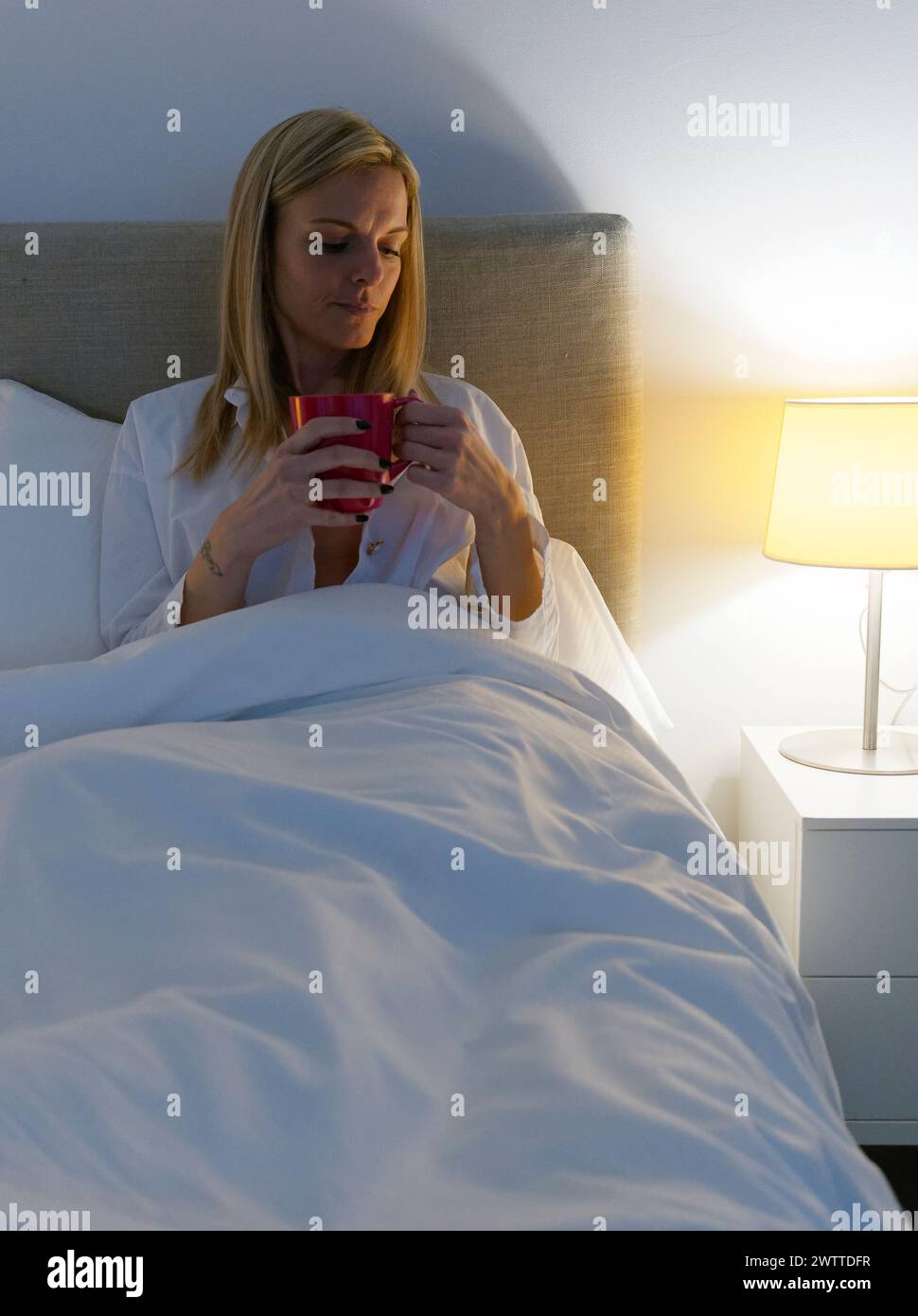 Sereni momenti mattutini mentre una donna si gode il suo caffè a letto Foto Stock