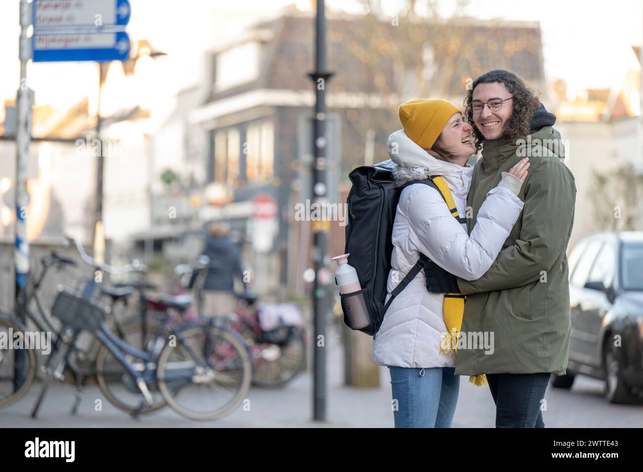 Due persone condividono un caldo abbraccio su una strada soleggiata della città. Foto Stock