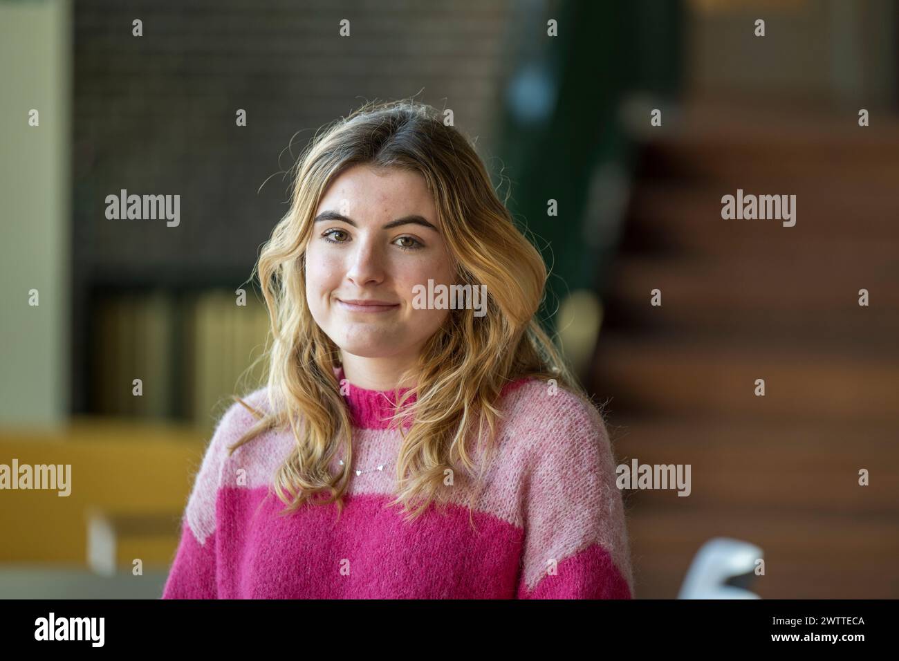 Giovane donna sorridente in interni con sfondo morbido Foto Stock