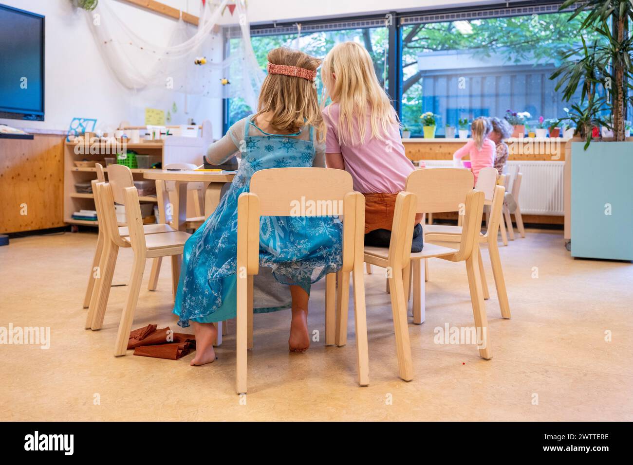 Due bambini impegnati in attività presso un tavolo in classe illuminato. Foto Stock