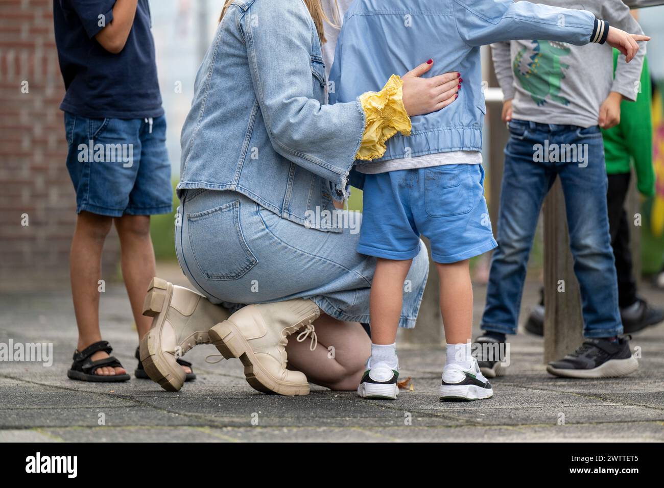 Madre accovacciata accanto a un bambino sul marciapiede della città. Foto Stock