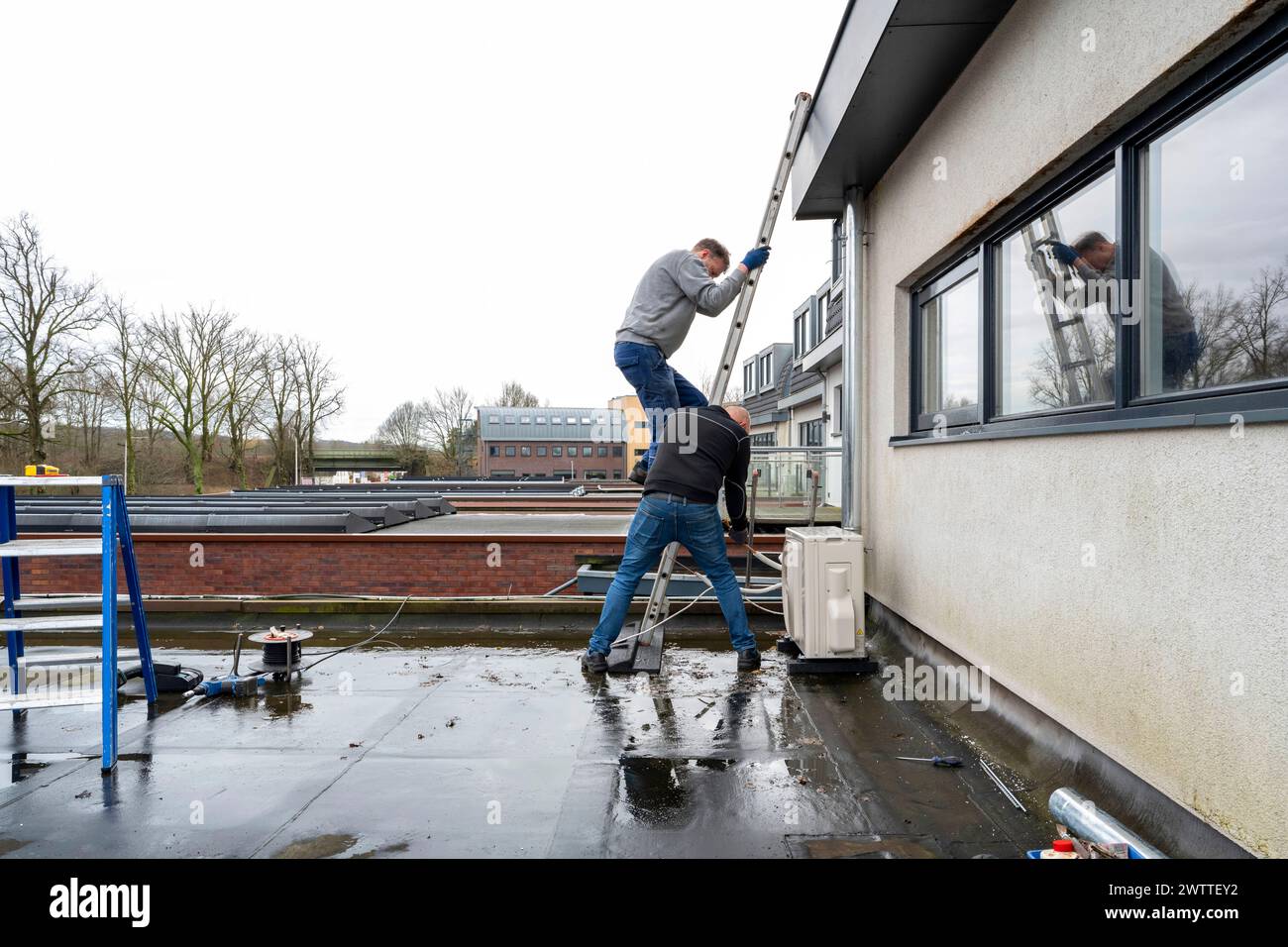 Due operai che installano una finestra in un giorno coperto. Foto Stock