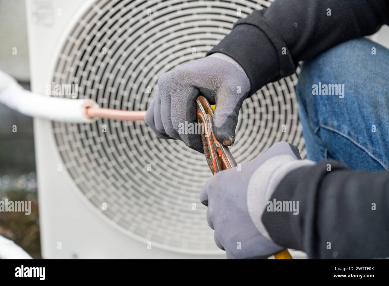 Un tecnico addetto alla manutenzione di un'unità di climatizzazione esterna. Foto Stock
