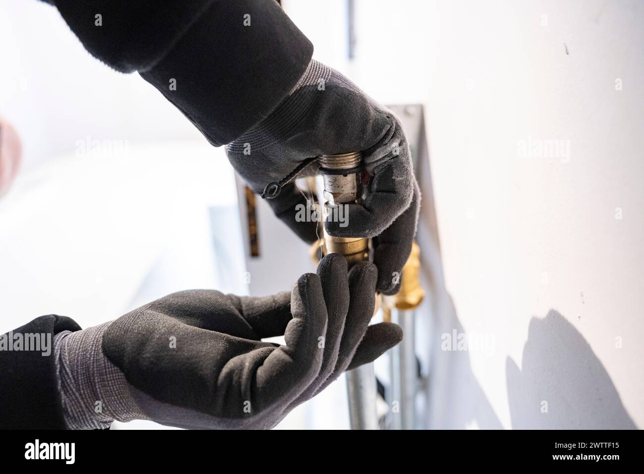 Mani che regolano con cautela una lampadina in un apparecchio. Foto Stock