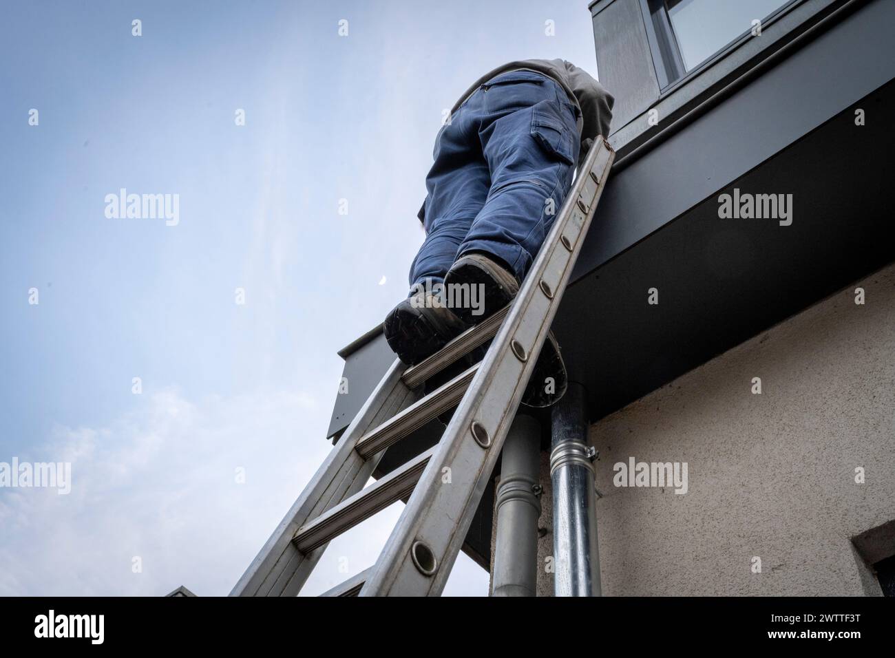 Uomo che sale una scala contro un edificio. Foto Stock