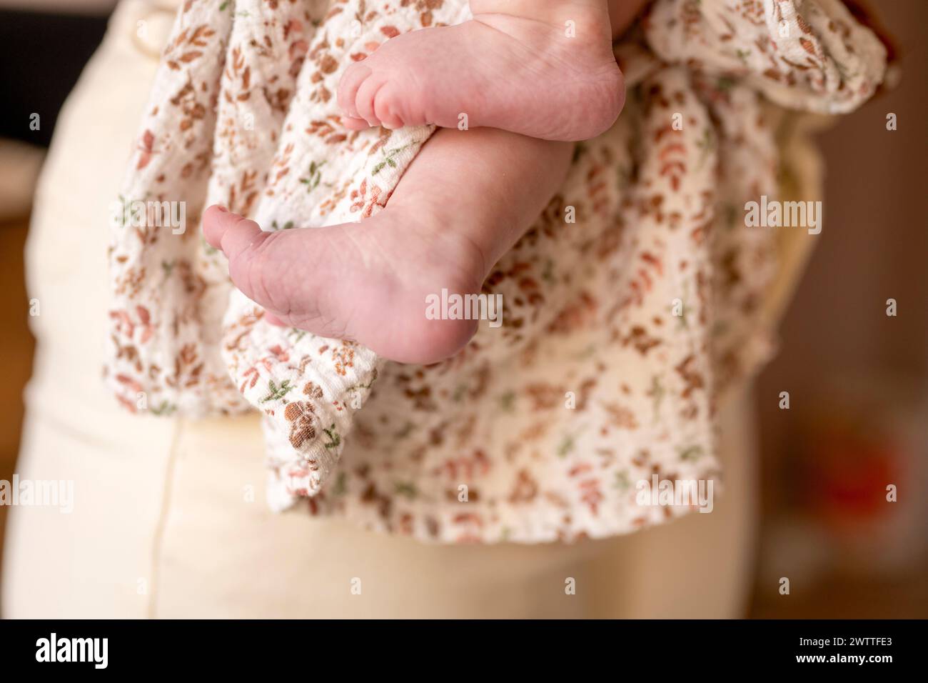 I piccoli piedini del bambino si cullano delicatamente tra le braccia della madre Foto Stock