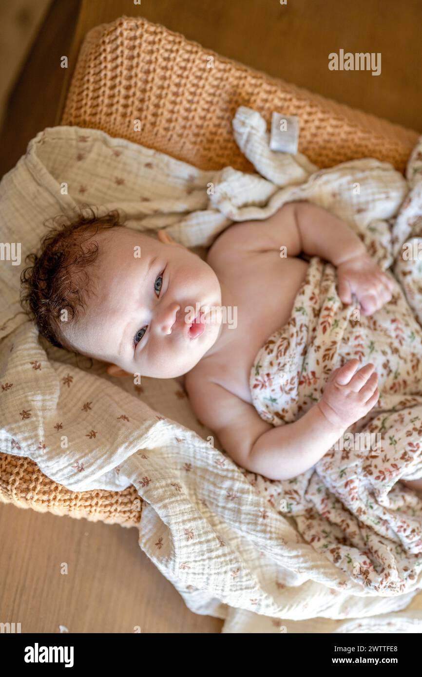 Un bambino simpatico che si sdraia comodamente su coperte morbide Foto Stock