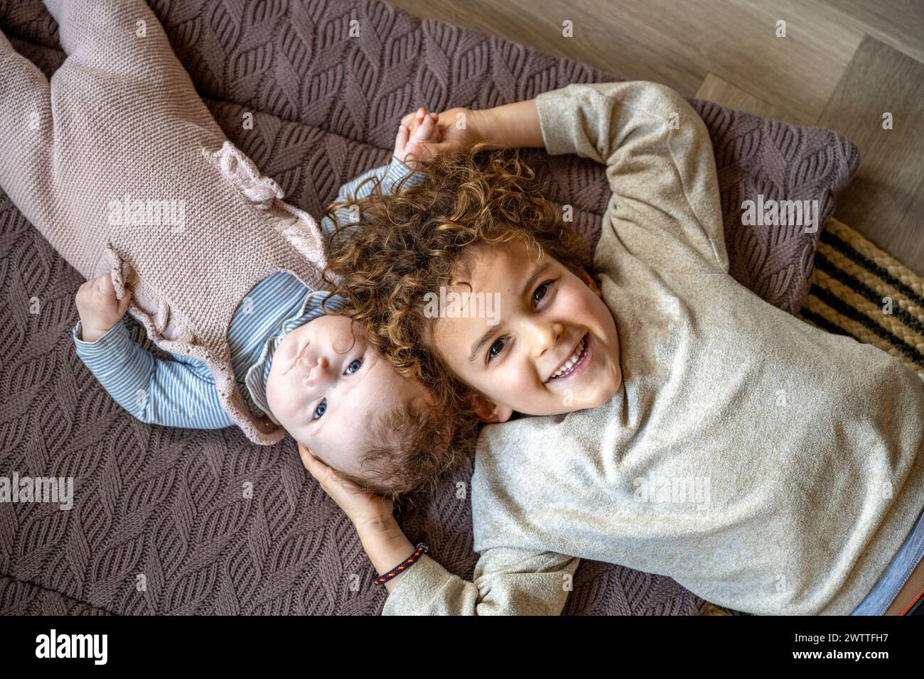 Due fratelli che si godono un momento di gioco insieme su un comodo divano. Foto Stock