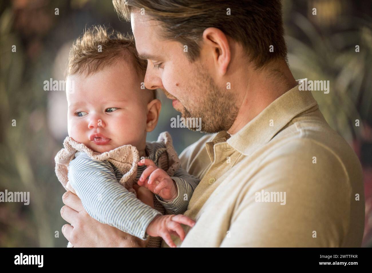 Padre amorevole che tiene in braccio il suo adorabile bambino Foto Stock
