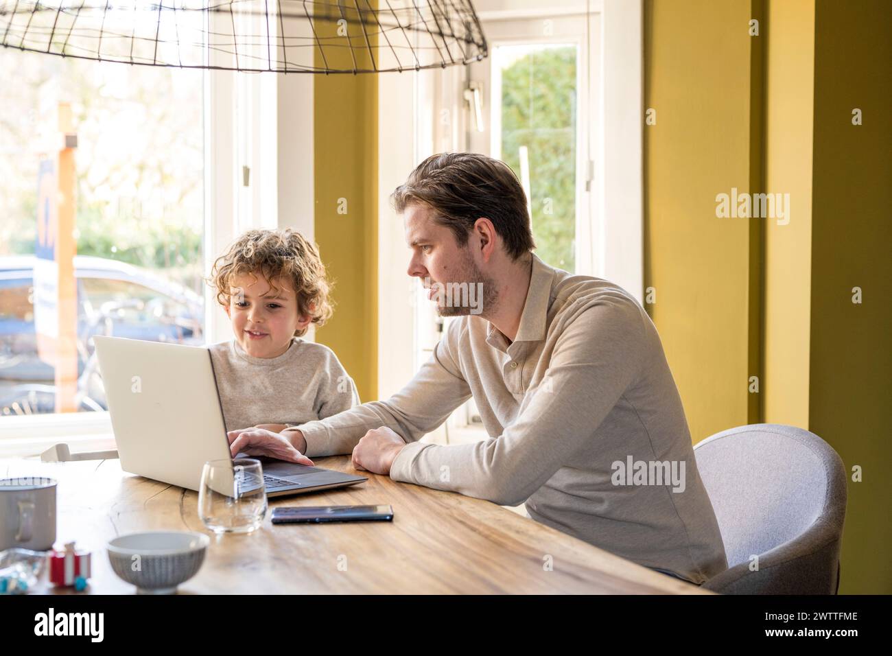 Adulto che insegna a un bambino di utilizzare un notebook in un ufficio domestico. Foto Stock