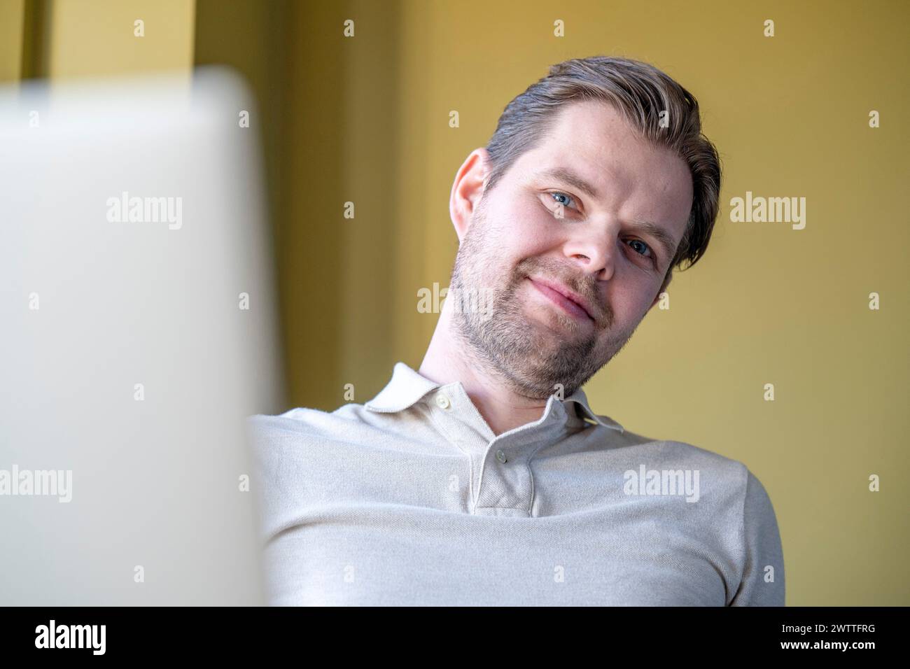 Uomo sorridente allo schermo del suo computer in un ufficio domestico Foto Stock