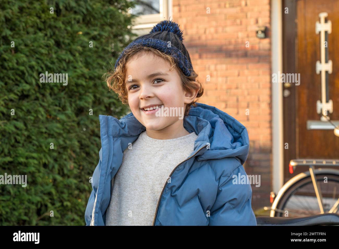 Bambino sorridente in un abbigliamento invernale che gode di una giornata di sole all'aperto. Foto Stock