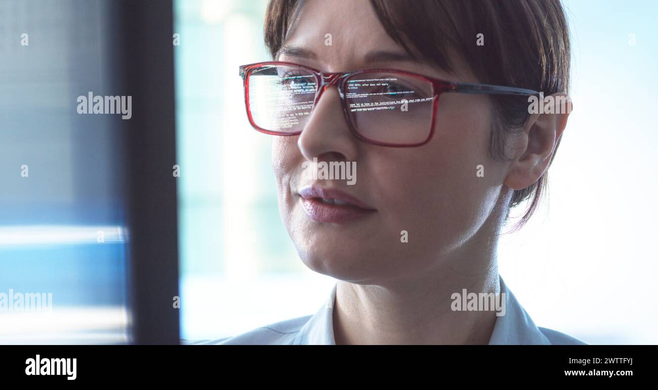 Programmatore donna che progetta il codice su uno schermo di un computer in ufficio. Foto Stock