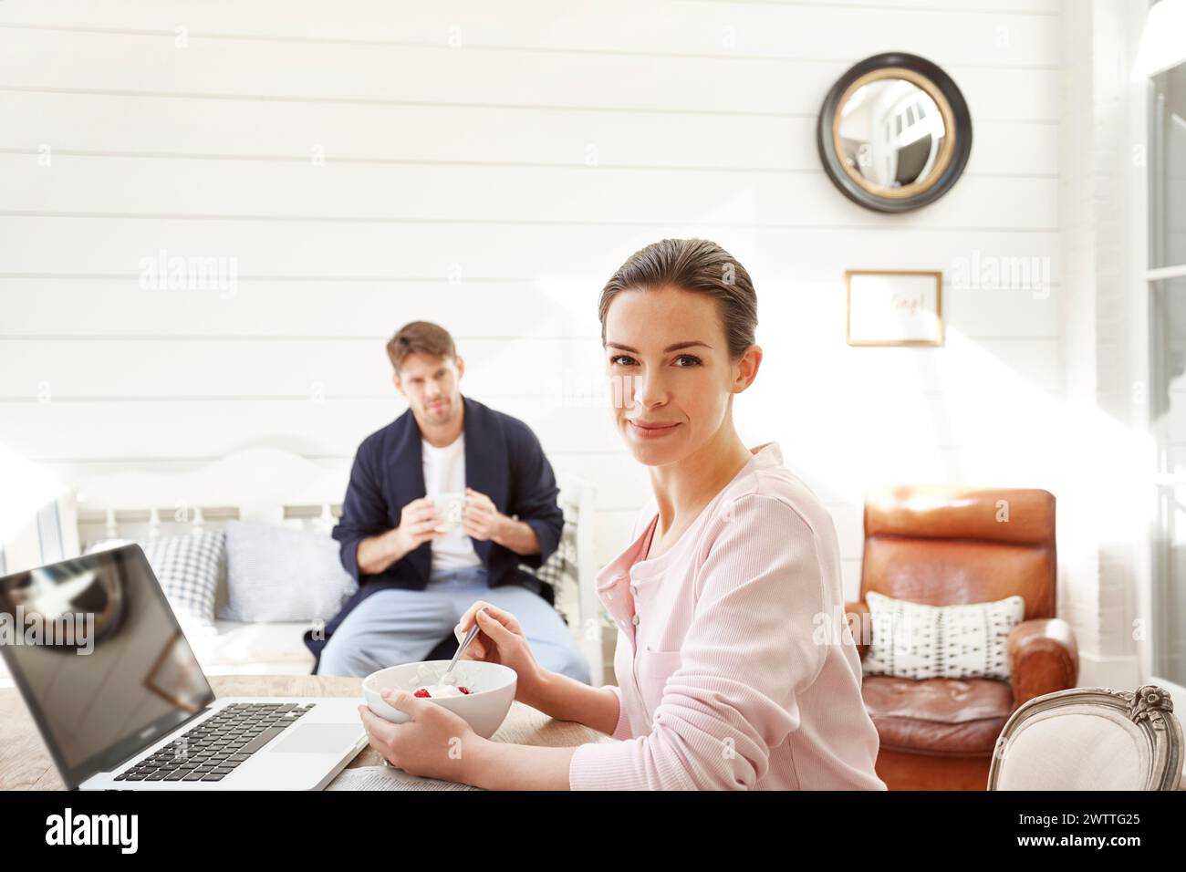 Donna con laptop e uomo che beve caffè a casa Foto Stock