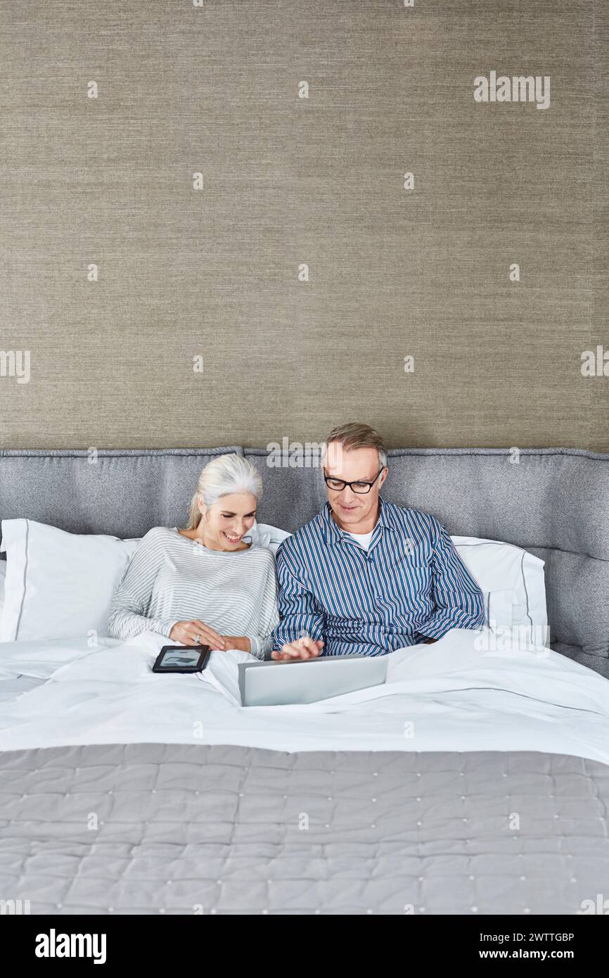 Coppia di anziani con il computer portatile a letto Foto Stock