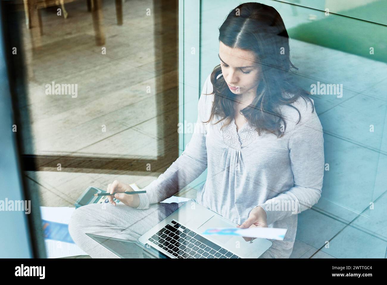 Donna che lavora su un notebook dietro un vetro Foto Stock