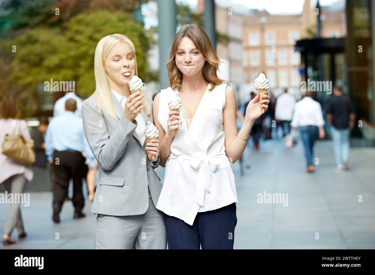 Due donne mangiano gelato mentre camminano Foto Stock