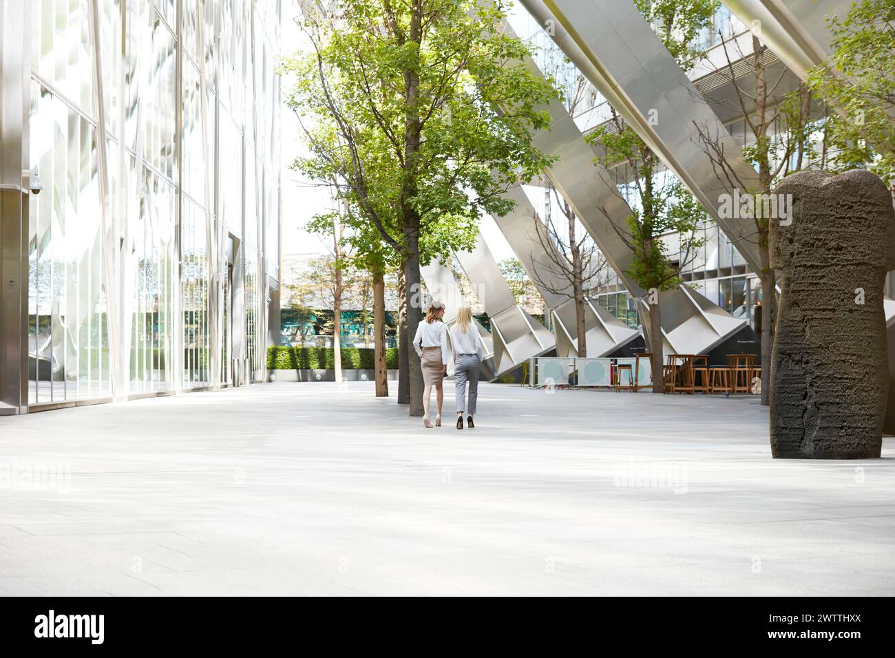Due persone camminano tra edifici e alberi moderni Foto Stock
