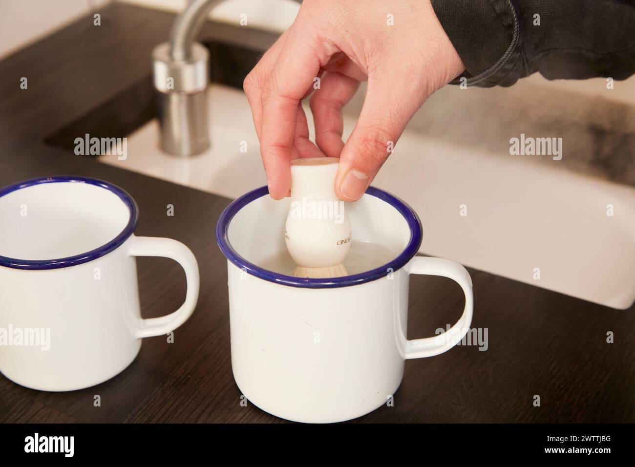 Immergere a mano un uovo in una tazza d'acqua Foto Stock