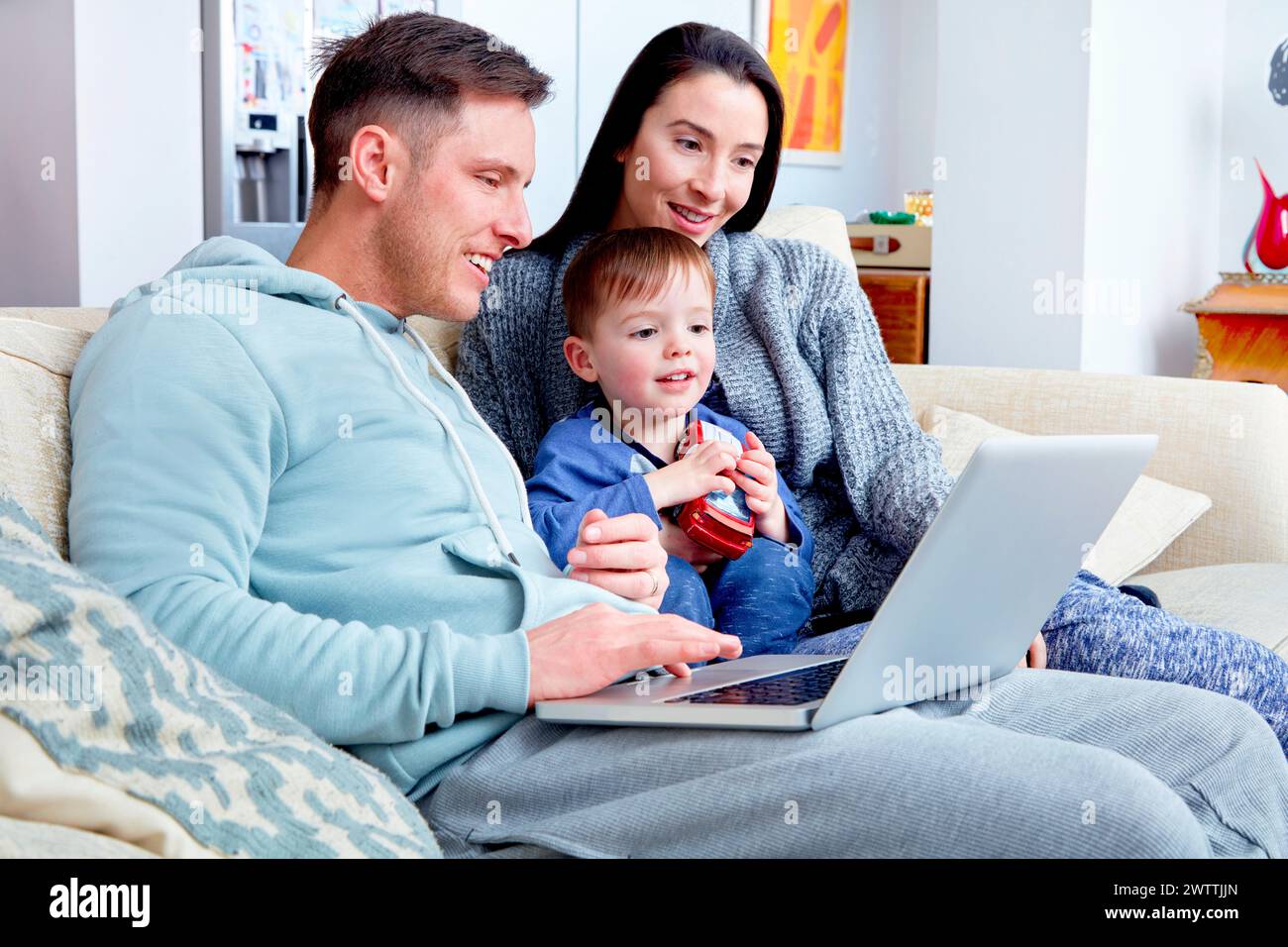 Famiglia con bambino che usa un laptop su un divano Foto Stock