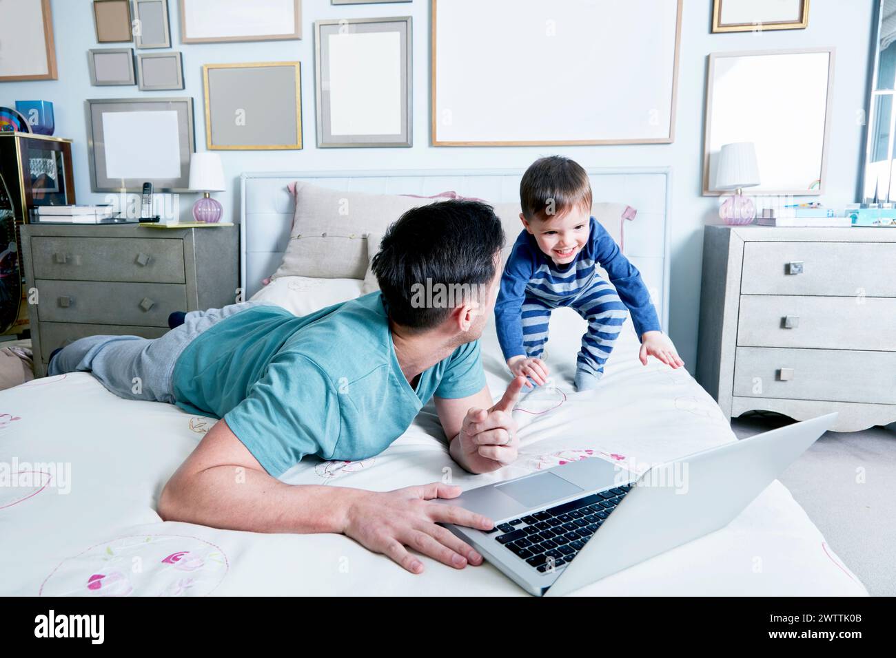 Bambino e adulto con un computer portatile sul letto. Foto Stock
