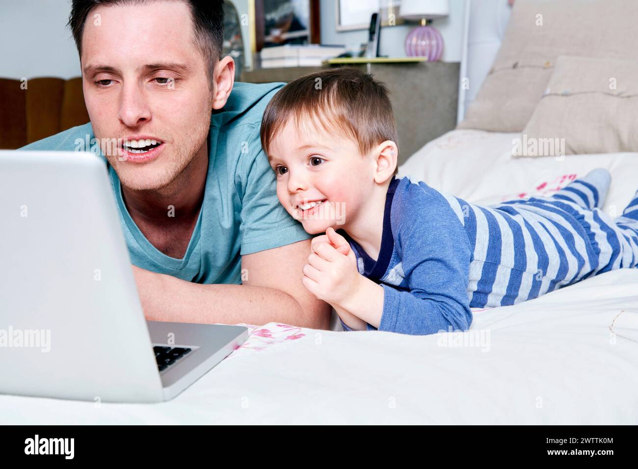 Uomo e bambino che guardano lo schermo del notebook sul letto. Foto Stock