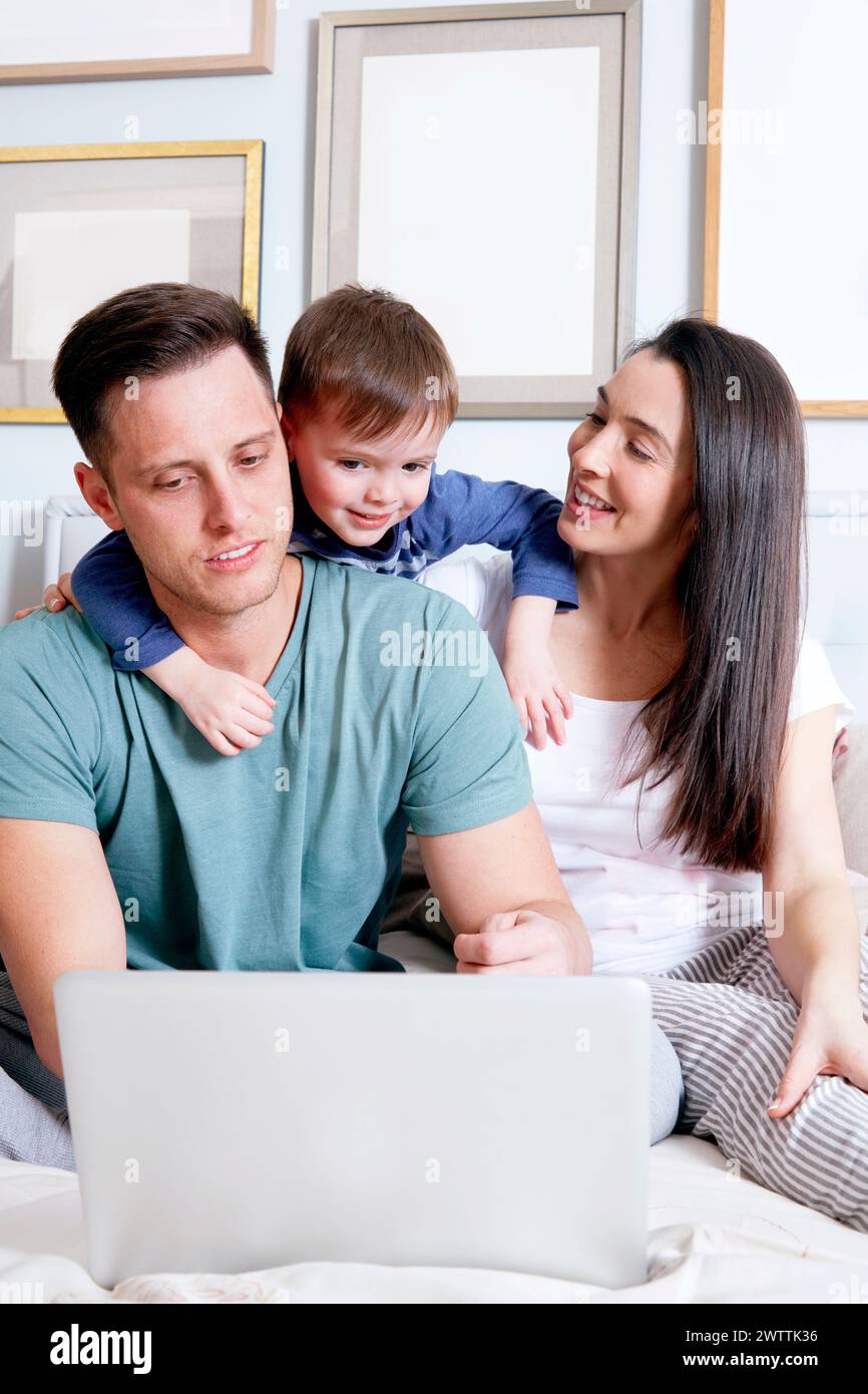 Famiglia con un bambino e un notebook seduti insieme Foto Stock