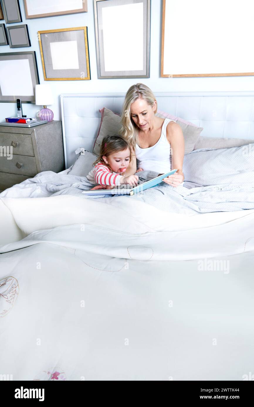 Madre e figlio leggono un libro a letto. Foto Stock