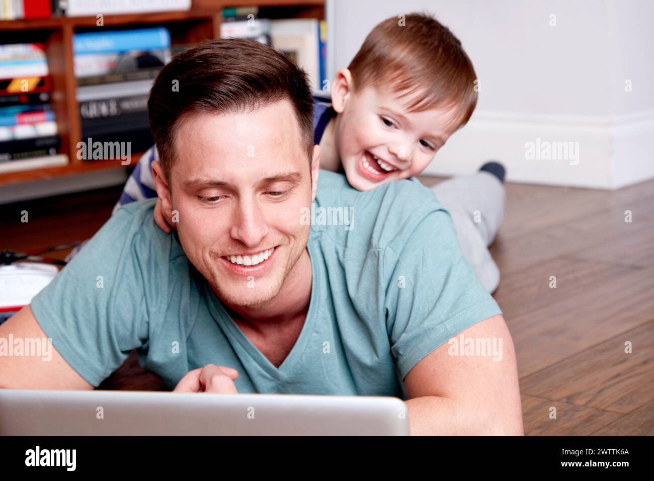 Uomo e bambino sorridono mentre usano un notebook insieme Foto Stock