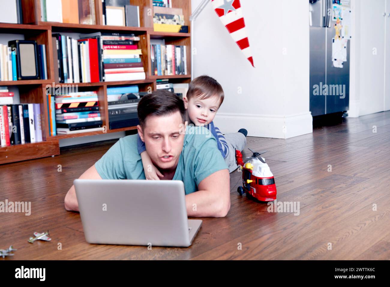 Padre e figlio che usano un notebook sul pavimento Foto Stock
